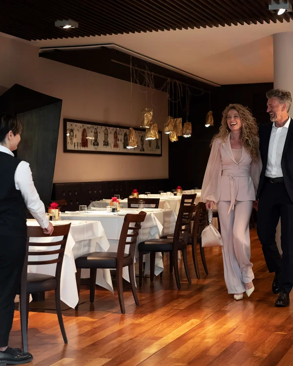 Elegant couple welcomed by waiter in modern restaurant