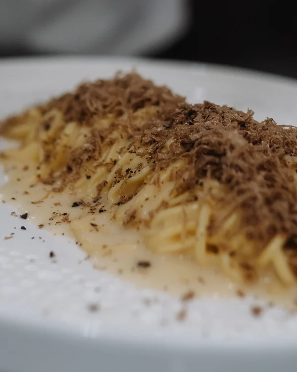 Chef grattugia tartufo su piatto di pasta