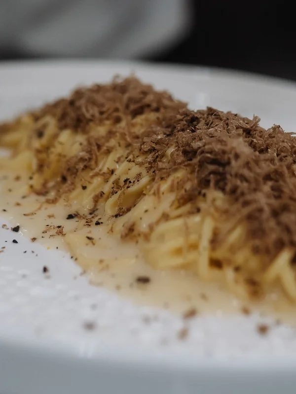 Chef grating truffle over pasta dish