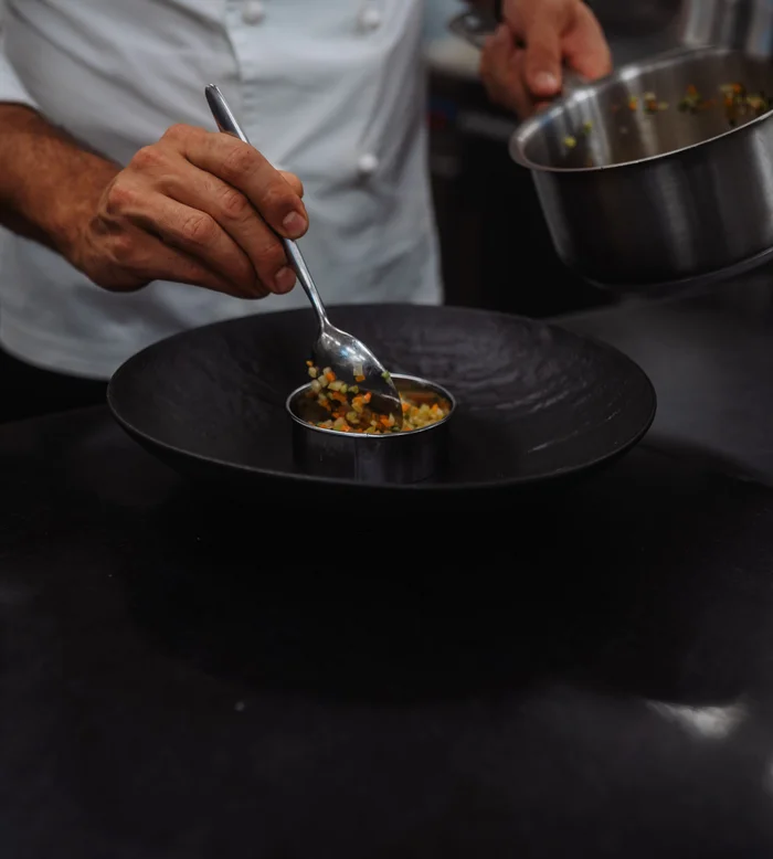 Chef che impiatta verdure tritate in cucina professionale