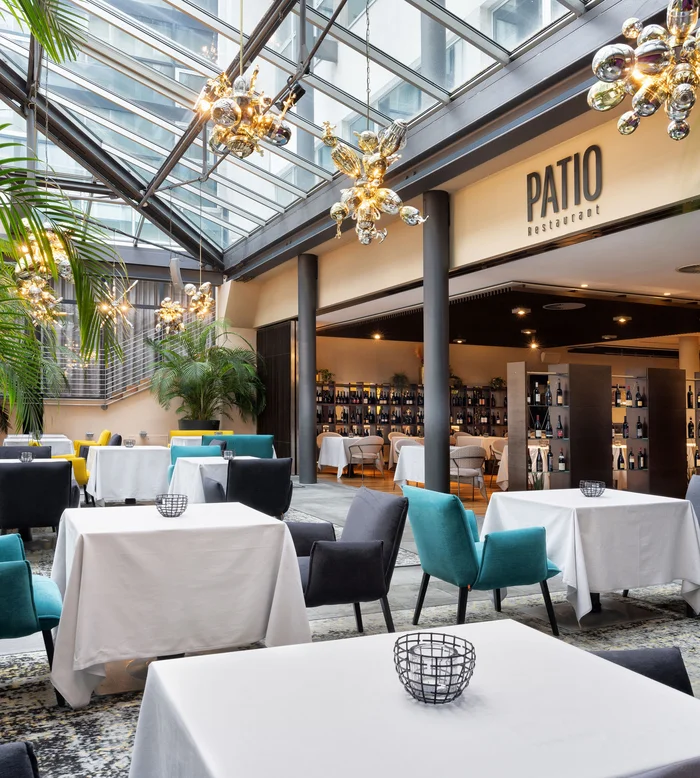 Ristorante Patio con tavoli apparecchiati e sedie colorate sotto un tetto di vetro