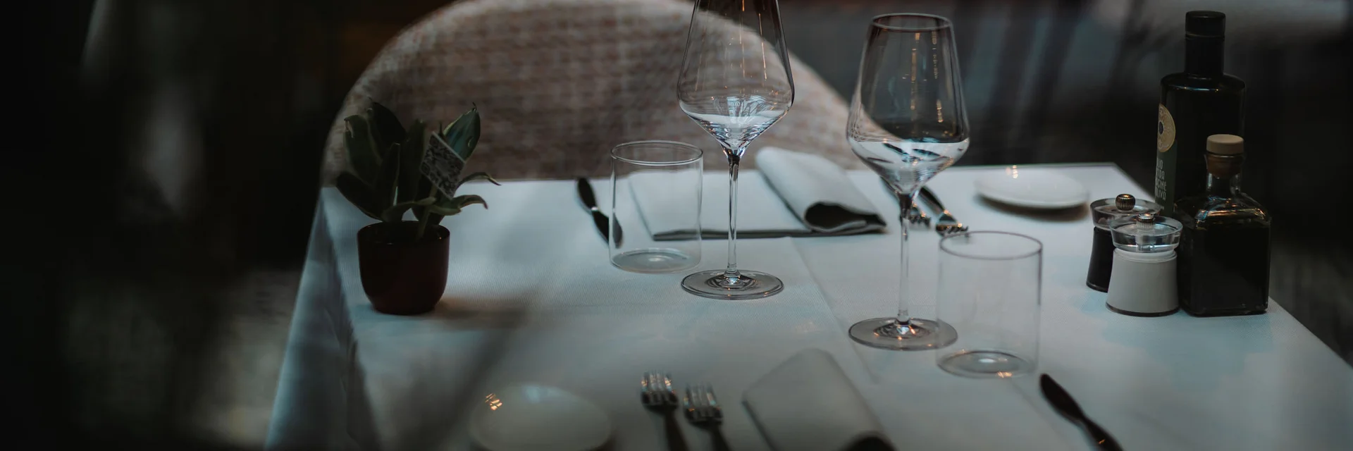 Tavolo apparecchiato con bicchieri, posate e bottiglie in ambiente accogliente