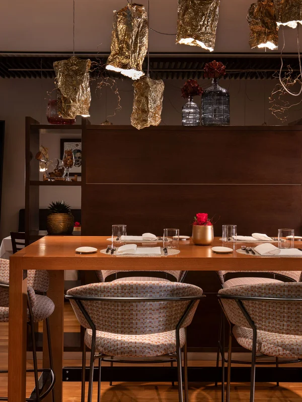 Sala da pranzo elegante con luci pendenti dorate e sedie imbottite.