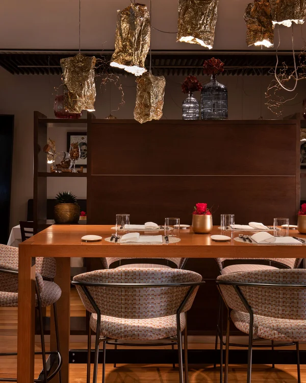 Elegant dining room with gold pendant lights and upholstered chairs.